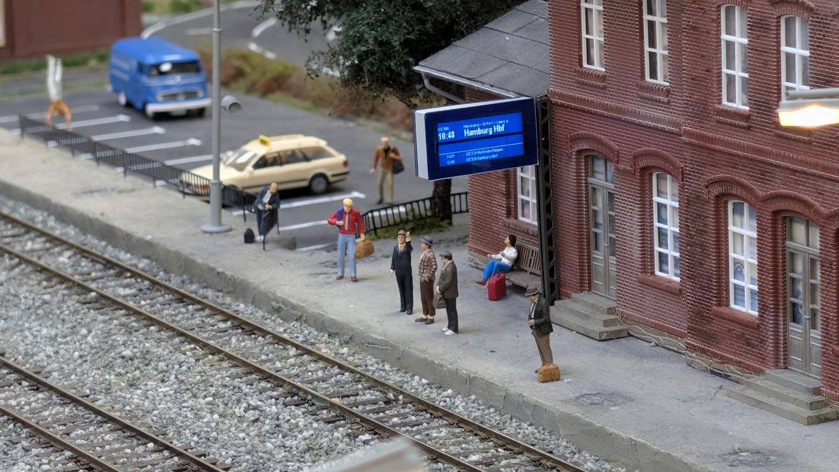 Zugzielanzeiger am Bahnsteiggeb&auml;ude, Bahnsteigszene mit wartenden Figuren