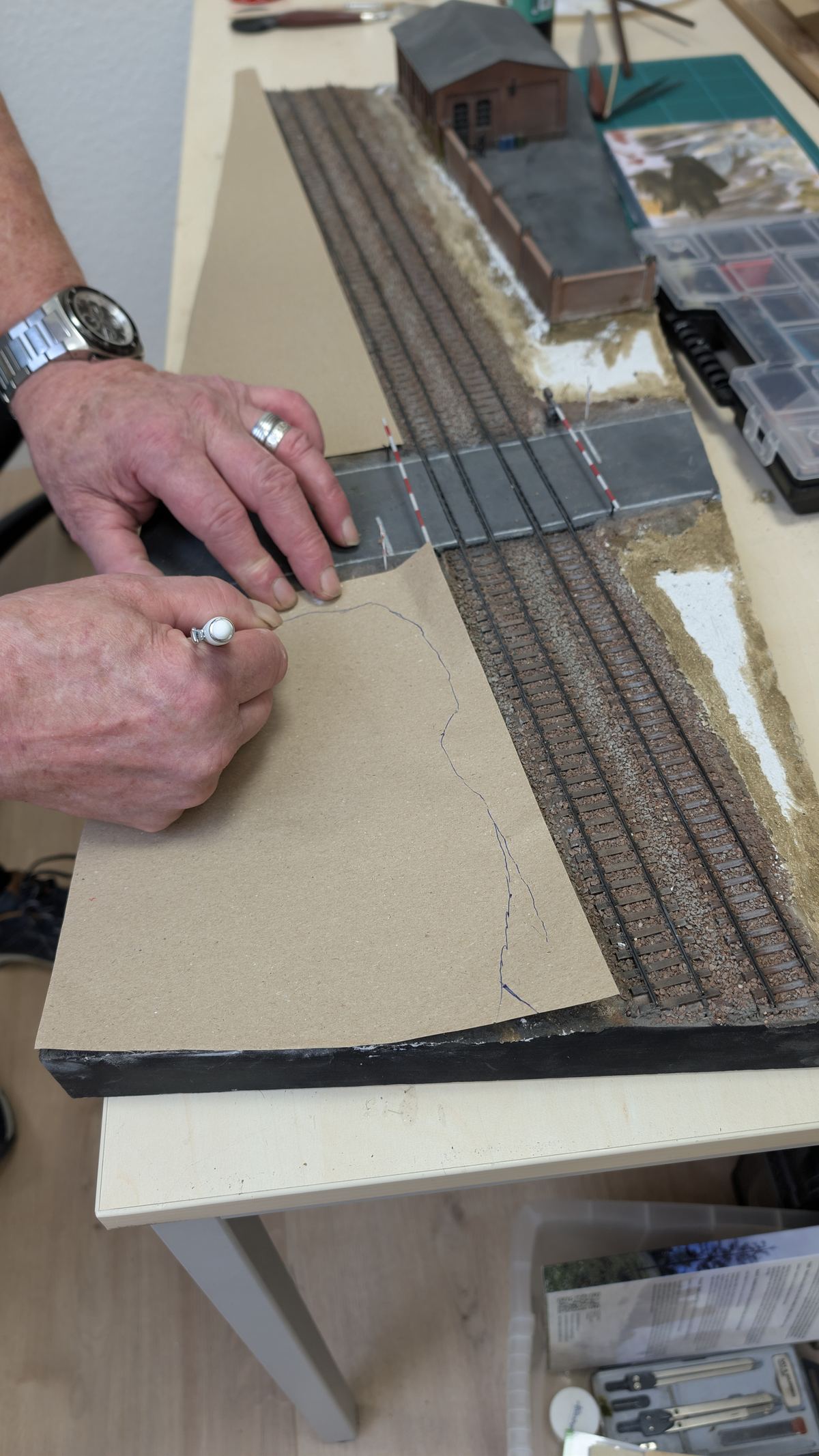 Hand zeichnet die Umrisse der Gel&auml;ndefl&auml;che auf aufgelegtes Packpapier